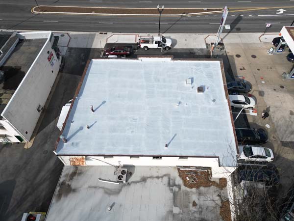 Aerial view of the 2330 Columbia Pike building with the full roof coated in grey PM P-160 bleed-block primer before silicone application