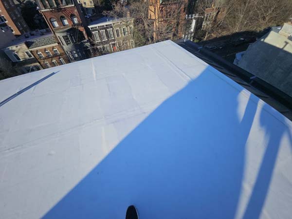 Completed TPO membrane carried over a roof ridge at 1530 P St NW, overlooking Washington, DC rowhouses below