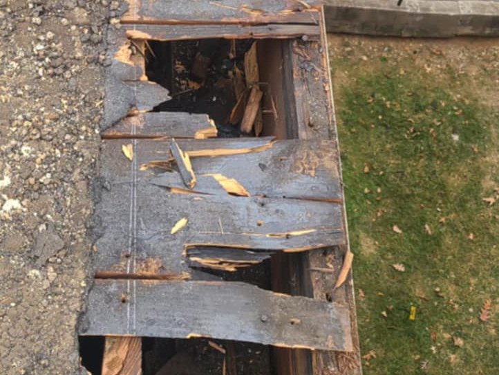 Rotted and splintered wood roof decking exposed along the gutter line at 2801 Pennsylvania Ave SE, with holes opening through to daylight