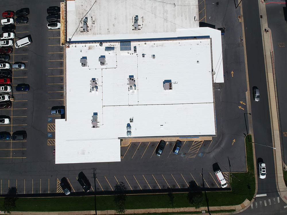 Overhead drone view of the completed white TPO roof on the shopping center at 150 E Wolfe St, Harrisonburg, VA, with rooftop HVAC units